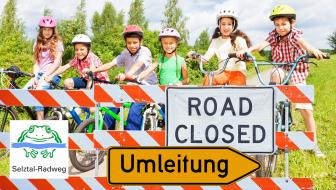 Eine Gruppe Kinder auf Fahrrädern steht hinter einer Straßenabsperrung
