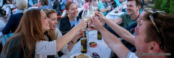 Menschen auf einem Fest sitzen am Tisch und prosten sich zu - Foto von Bernward Bartram